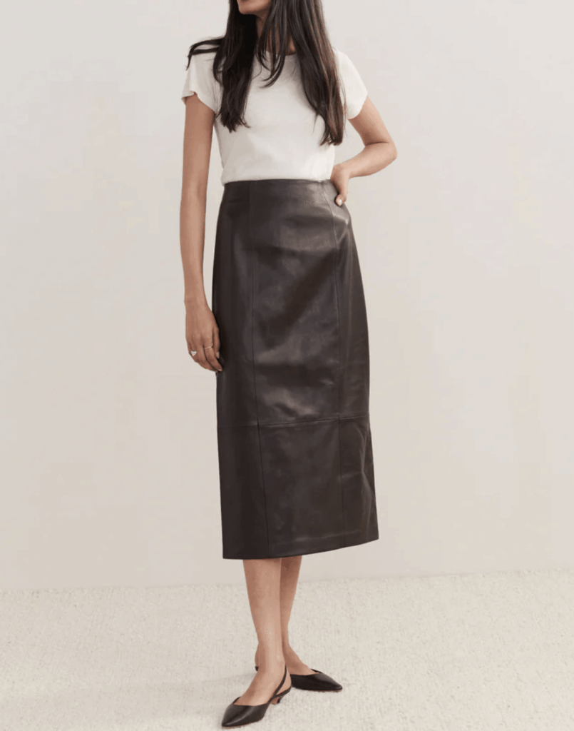 woman with long dark hair modeling brown leather skirt, white t-shirt, and black flats